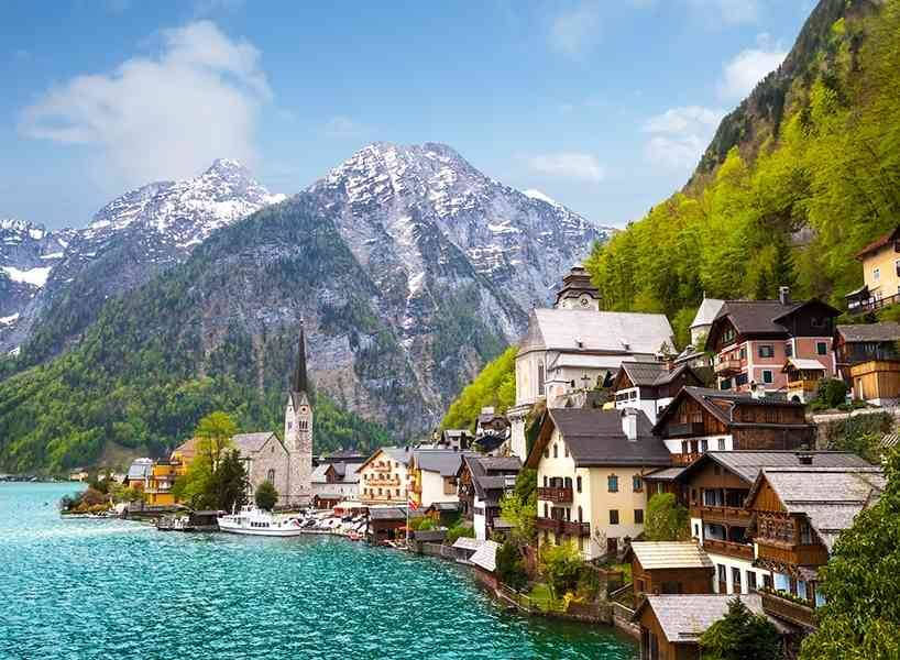 A blue water body, modern structures with a visible mountainous background.